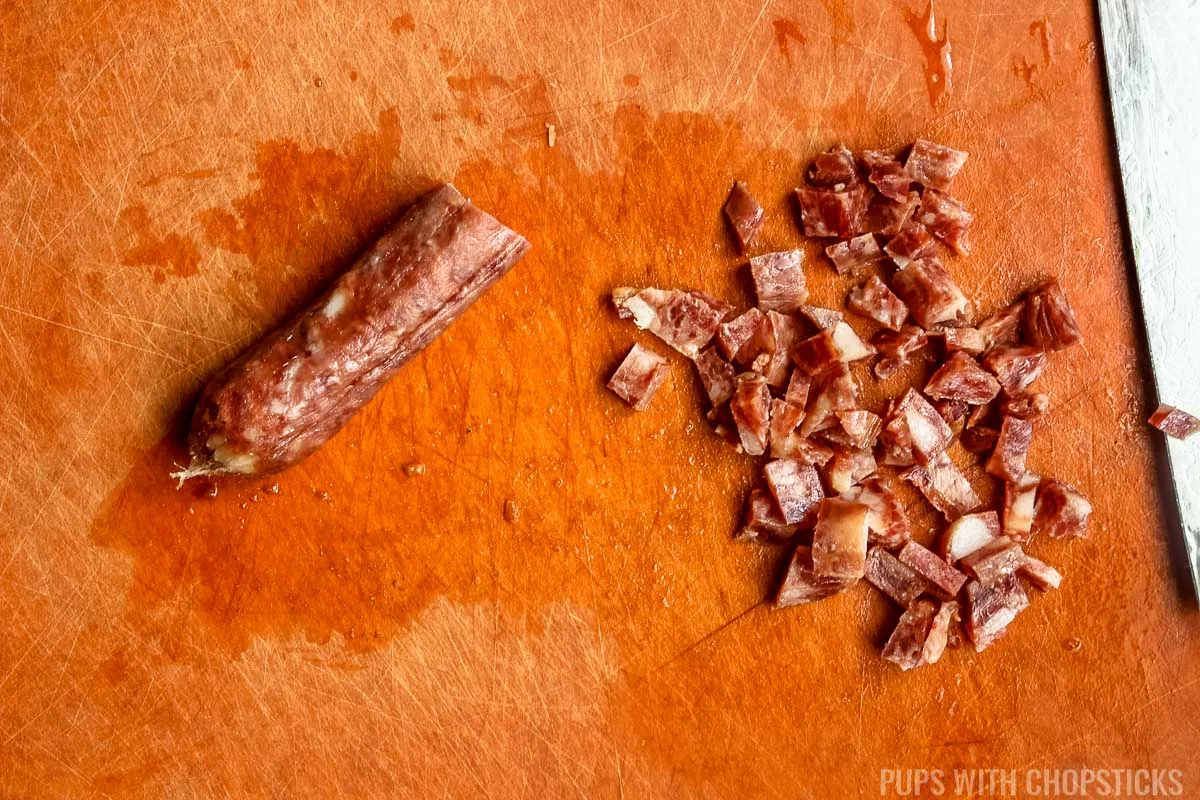 dicing chinese sausage on cutting board.