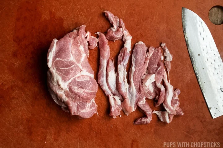 cutting the slices of pork shoulder into strips.