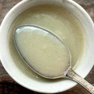 Closeup of Chinese white sauce on a spoon in a white bowl.
