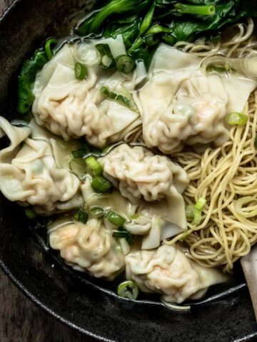 A large bowl of wonton noodle soup with wonton noodles, dumplings and Chinese vegetables.