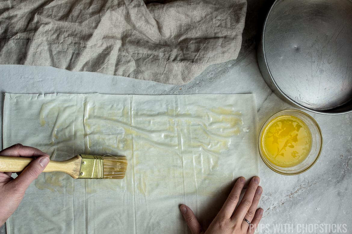 Butter being brushed on a sheet of phyllo for Black Sesame Chocolate Ruffled Milk Pie recipe