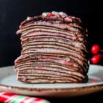 A slice of Candy Cane Chocolate Crepe Cake on a plate on a table