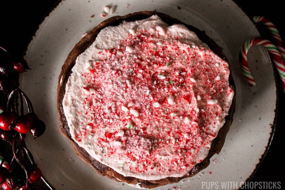 Sprinkling candy cane bits over whipped cream on crepe for Candy Cane Chocolate Crepe Cake