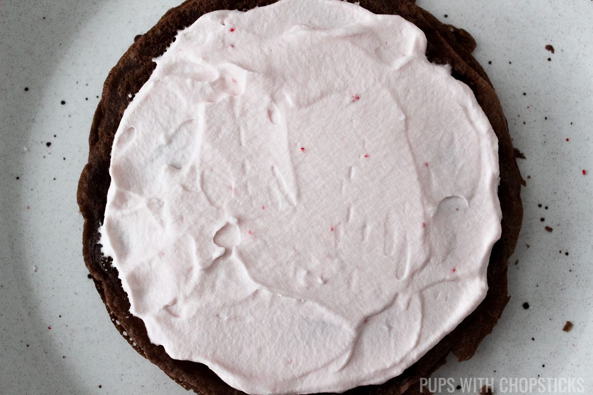 Spreading candy cane whipped cream on crepe layer for Candy Cane Chocolate Crepe Cake