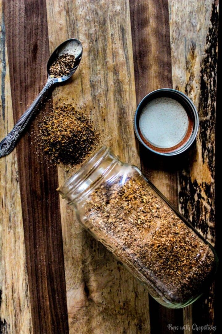 Coffee rub in a mason jar sprinkled onto a cutting board to show the spices.