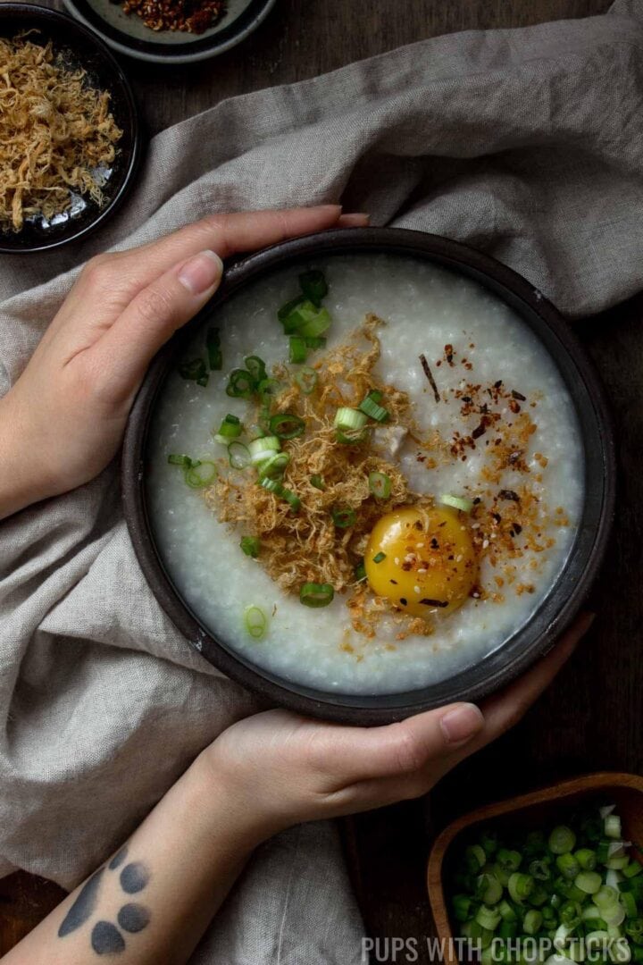 Holding a bowl of congee on a table