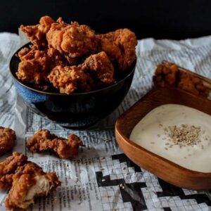 Crispy Buttermilk Popcorn Chicken in a bowl on a table with a side of sesame dip