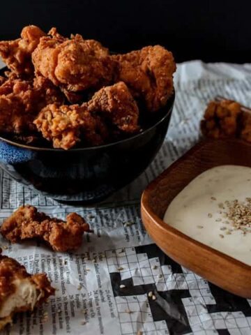 Crispy Buttermilk Popcorn Chicken in a bowl on a table with a side of sesame dip