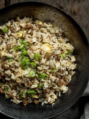Cumin Beef Fried Rice in a black bowl on wooden table