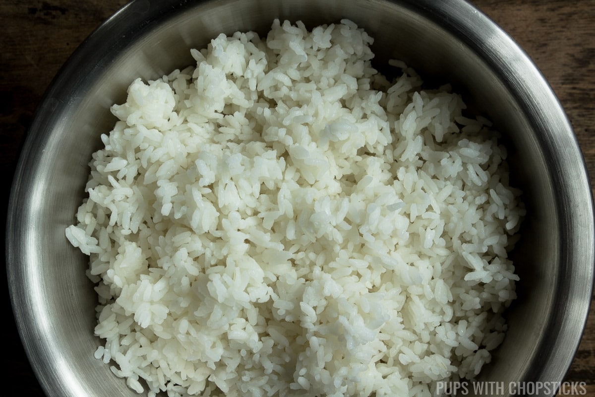 A bowl of leftover rice, broken up into small pieces, to show how large the chunks of rice should be before adding it to the frying pan.