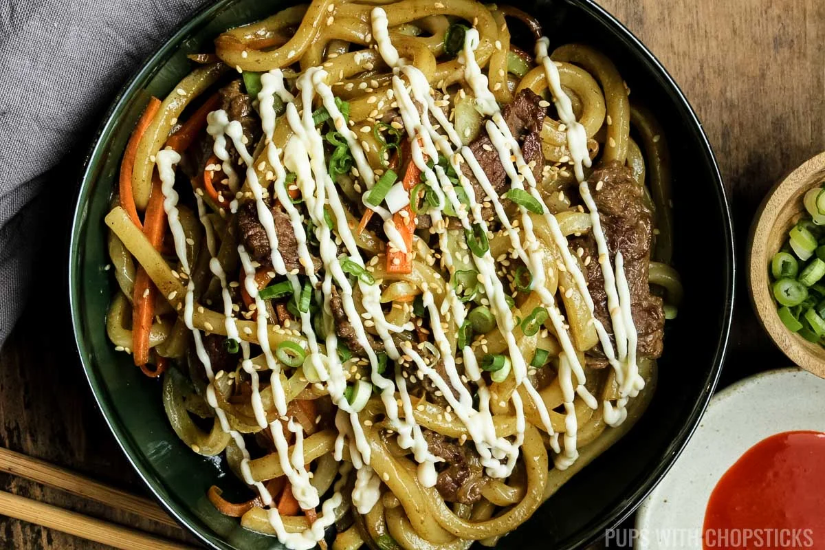 curry beef yaki udon with mayo on a green plate.