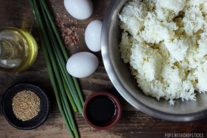 Rice, eggs, oil, green onions, soy sauce, salt, sesame seed ingredients on a wooden table