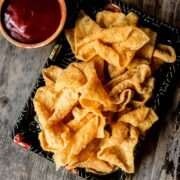 Chinese fried wonton strips on a takeout tray served with sweet and sour sauce