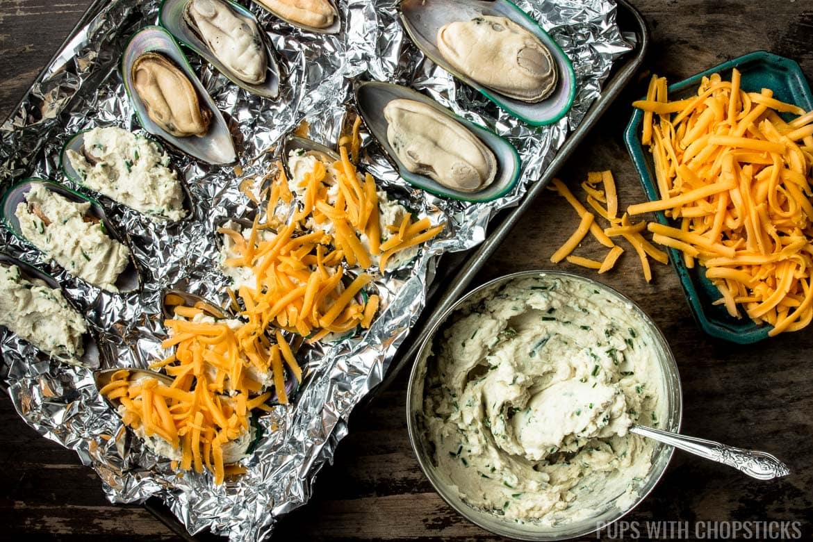 Mussels laid out on a sheet of crumpled tin foil on a baking sheet to showcase how to spread the cream cheese on