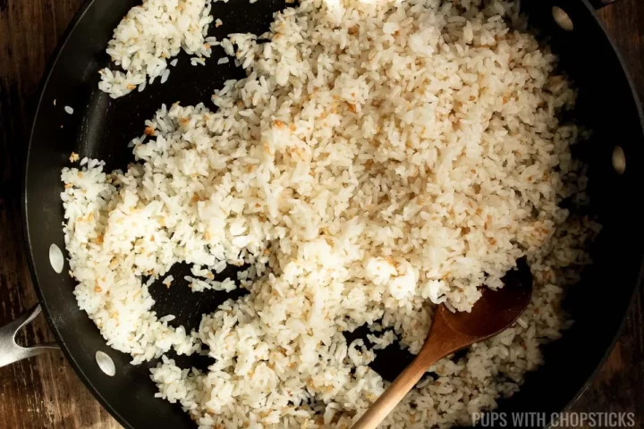 Stirring garlic fried rice with wooden spoon in a frying pan