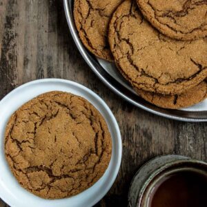 Five Spice Ginger Molasses cookies being served on a plate with a cup of tea on the side