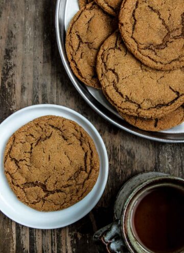 Five Spice Ginger Molasses cookies being served on a plate with a cup of tea on the side
