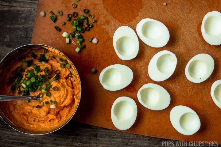 A bowl of cooked egg yolks mixed with gochujang, mayonaise and green onions, being ready to be scooped back into egg whites