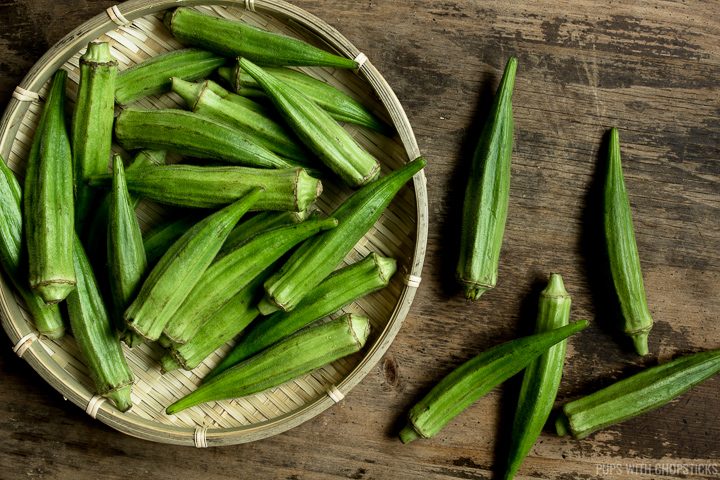 Fresh raw okra in a basket on a wooden table