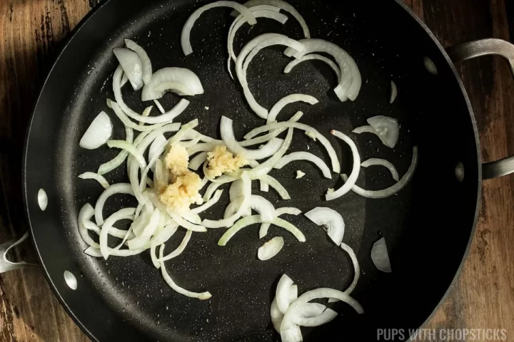 A frying pan with onions and garlic.
