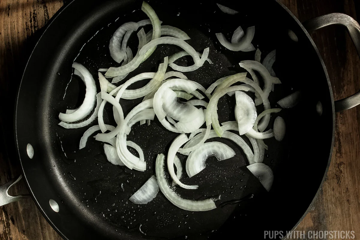 Onion being stir-fried in a frying pan.