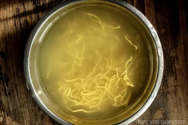 Hakka noodles being soaked in boiling water.