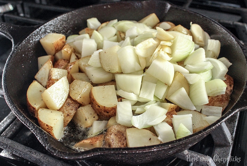 Skillet Potatoes Infused with Caramelized Onions being cooked in a skillet