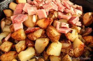Skillet Potatoes Infused with Caramelized Onions, golden brown in a skillet with ham