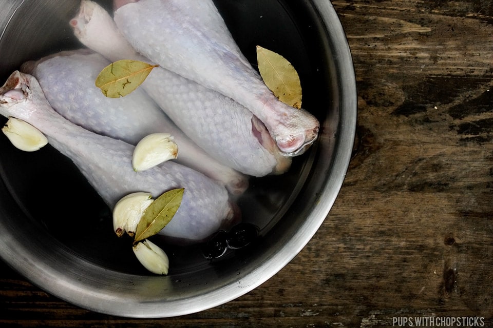 Herb Roasted Turkey Legs being brined in a large metal bowl