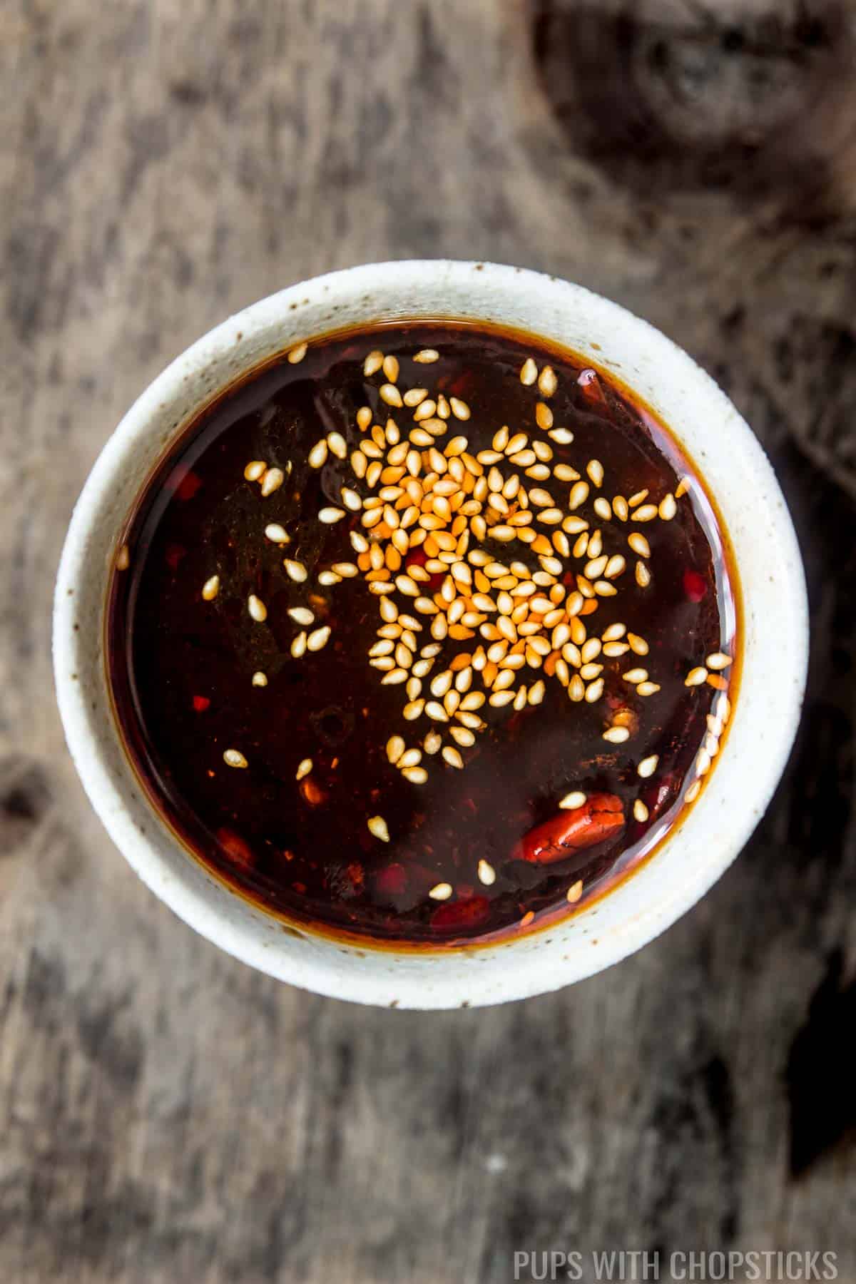 A close up of hoisin dipping sauce garnished with toasted sesame seeds.