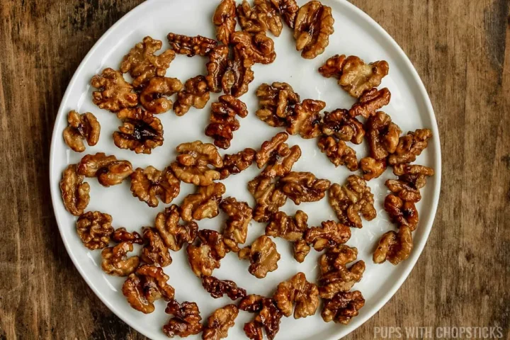 candied walnuts cooling on a white plate.