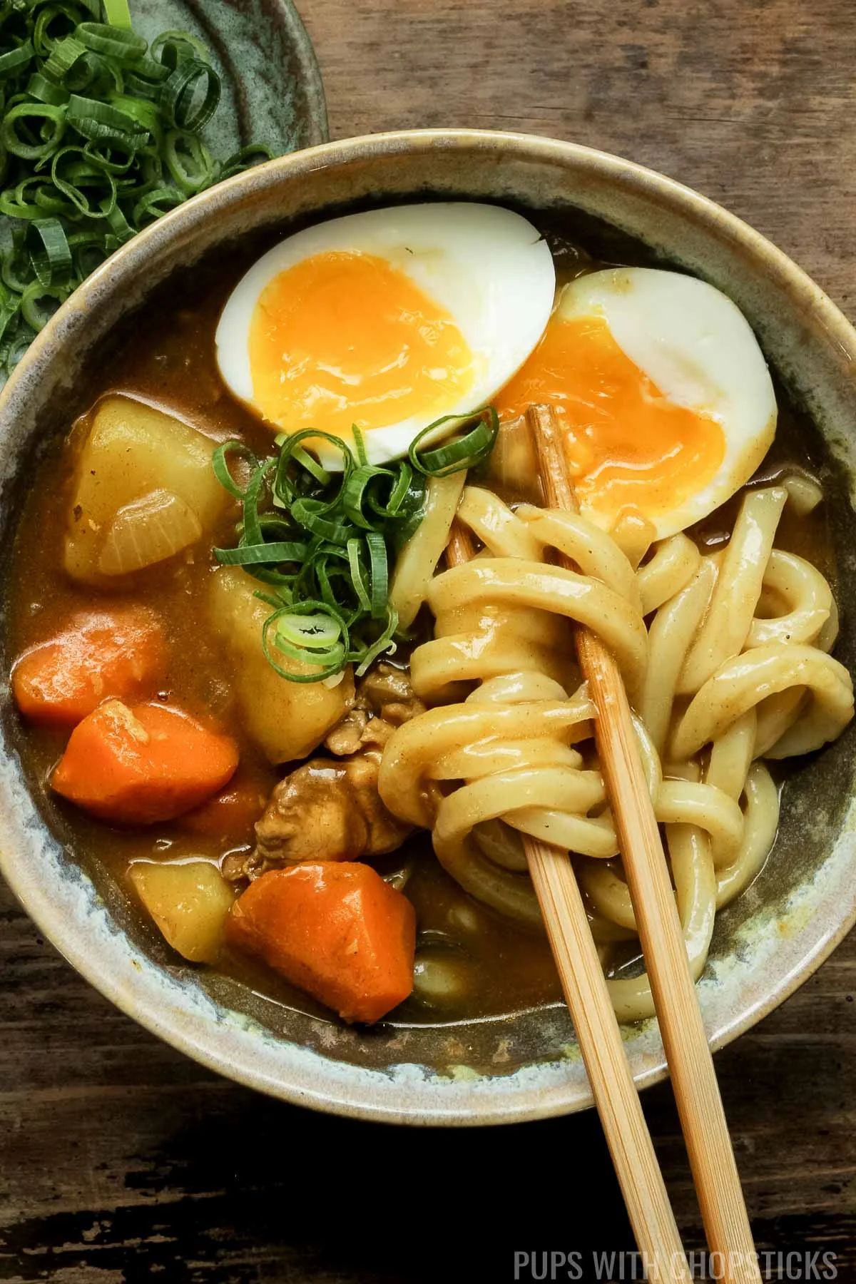 Japanese curry udon noodles being eaten with wooden chopsticks