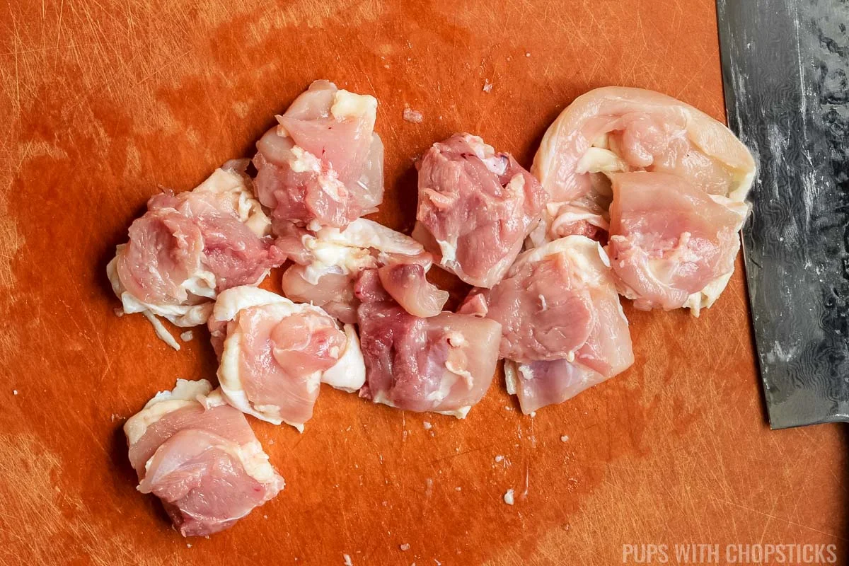 Chicken thighs cut into 1 inch pieces on a cutting board