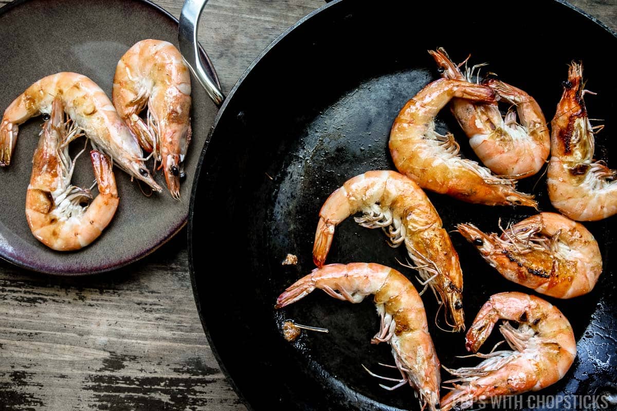 Shrimp being stir fried in a large frying pan.