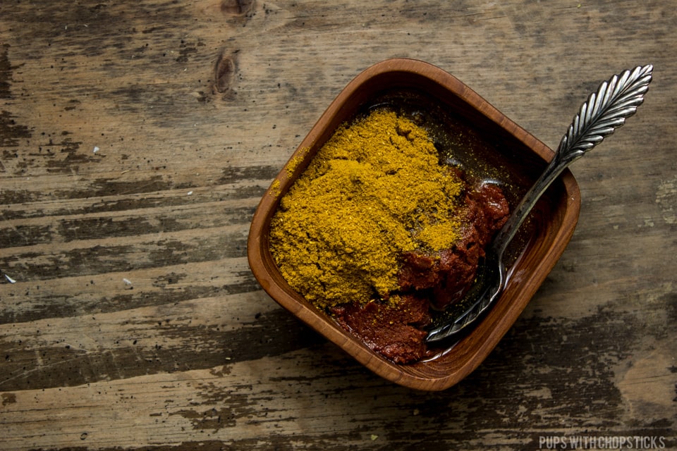 Quick and easy khao soi curry paste in a small bowl (red curry paste mixed with madras curry powder)