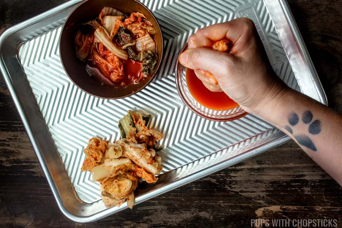 A person squeezing kimchi liquid out of kimchi for the kimchi fried rice.