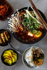 Spicy Tofu Kimchi Stew (Kimchi Jjigae) in a bowl with rice on a countertop
