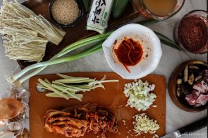 Preparation of cutting vegetables and kimchi on a counter top for Spicy Tofu Kimchi Stew (Kimchi Jjigae)