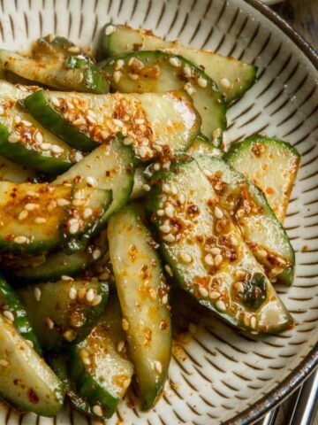 Close up of Korean cucumber salad on a small beige plate.