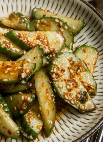 Close up of Korean cucumber salad on a small beige plate.