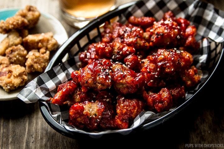 A basket of Korean fried popcorn turkey nuggets coated with a red sweet and spicy gochujang sauce
