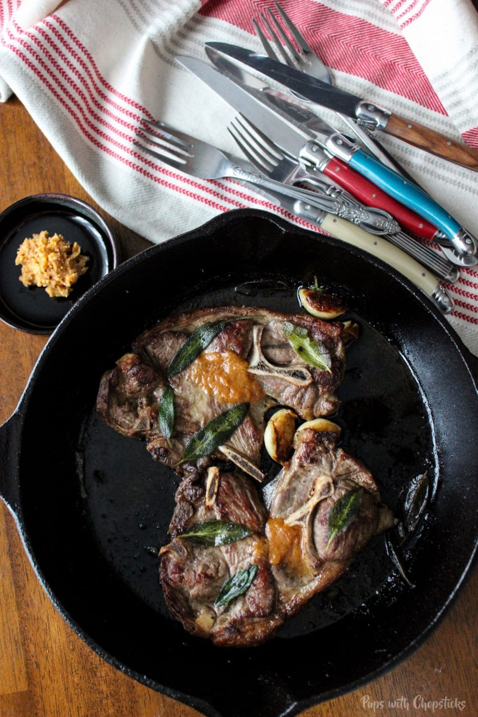 Pan Fried Lamb Chops with Miso Butter in skillet on table with utensils