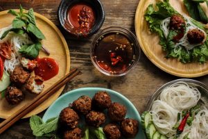Lemongrass Pork Meatballs (Larb Style) laid out on 3 plates with a small bowl of fish dipping sauce, hot sauce and vermicelli noodles.