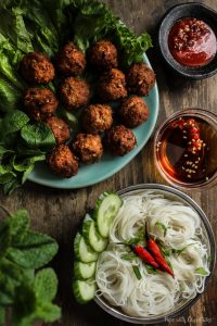 Lemongrass Pork Meatballs (Larb Style) in a large plate served with a side of vermicelli noodles, chilli sauce and fish sauce dipping sauce on a table