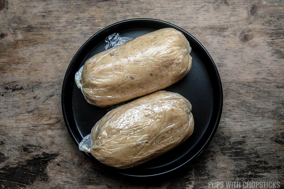 miso butter wrapped in plastic wrap, tube form on a black plate.