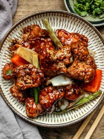 Mongolian chicken on a beige plate on a wooden table.