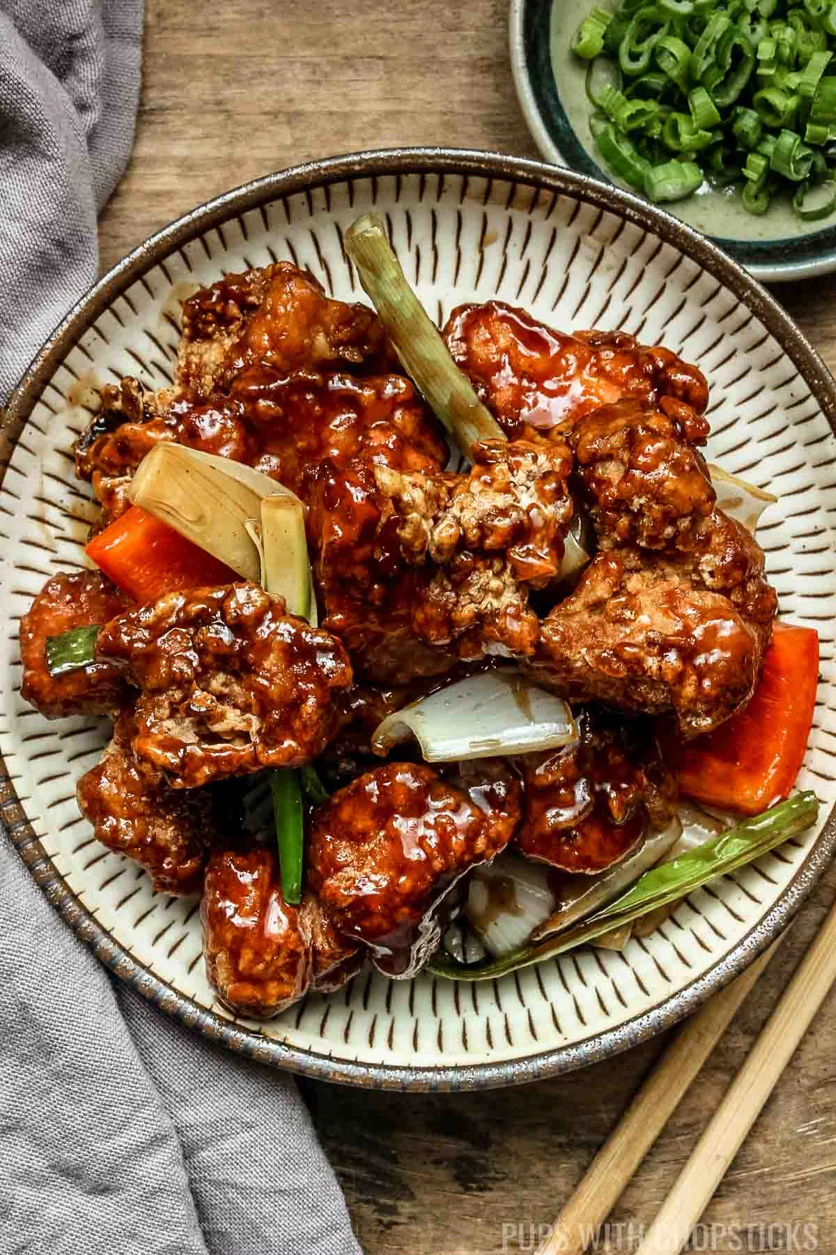 Mongolian chicken on a beige plate on a wooden table.