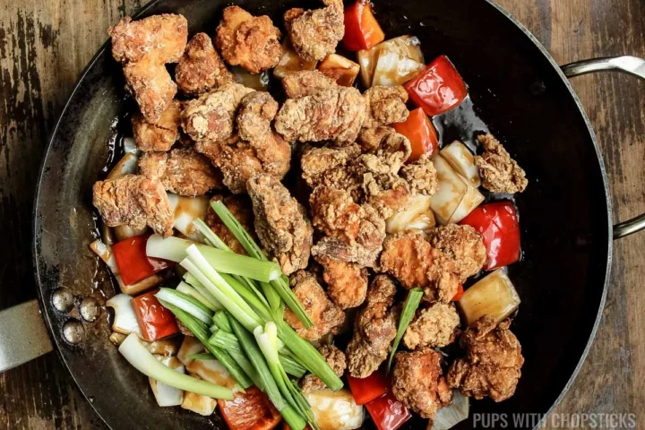 adding fried chicken, and green onions into frying pan.