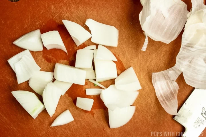 Cutting a white onion into large cubes.