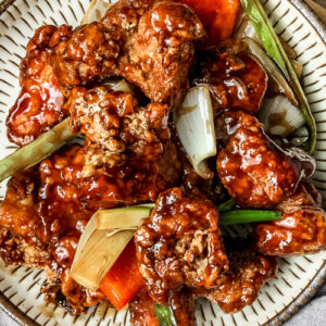 Thumbnail of Mongolian chicken on a beige plate on a wooden table.